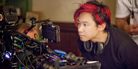 Jame Wan look at the camera with a headphone around his neck while filming.